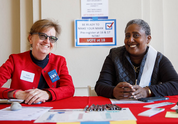 Photo of two LWV voluneers from Pasadena, California sitting at a voter registration table' both are smiling widely