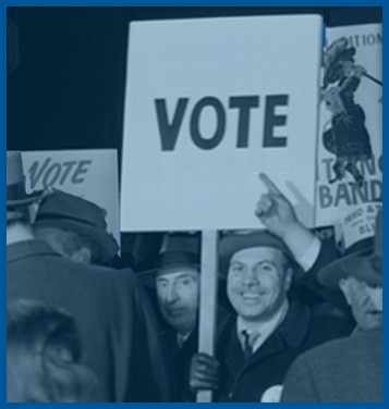 In this altered image, a happy man in a crowd of people carrying signs holds a large sign saying, simply, 'VOTE,' as another member of the crowd points to the word VOTE.